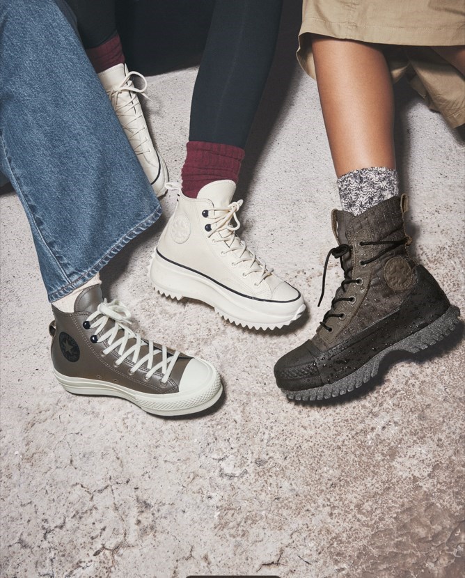 3 pary wysokich sneakersów na platformie Converse na nogach młodych osób